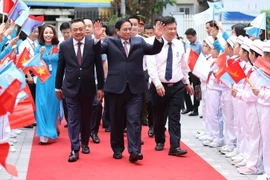 Các em học sinh Trường Tiểu học Đoàn Thị Điểm chào đón Thủ tướng Phạm Minh Chính và các đại biểu đến dự khai giảng. (Ảnh: Dương Giang/TTXVN)