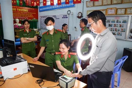 Cán bộ Công an phường Tân An, quận Ninh Kiều hướng dẫn người dân thực hiện đăng ký tài khoản định danh điện tử mức độ 2. (Ảnh: TTXVN phát)