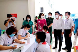 Thứ trưởng Bộ Y tế Nguyễn Thị Liên Hương, Phó Chủ tịch UBND tỉnh Vĩnh Phúc Vũ Việt Văn kiểm tra công tác tư vấn, khám sàng lọc cho các em học sinh trước khi tiêm vaccine phòng COVID-19. (Ảnh: Nguyễn Thảo/TTXVN)