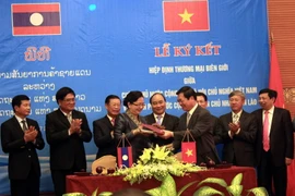 Bộ trưởng Bộ Công Thương Việt Nam Vũ Huy Hoàng và Bộ trưởng Bộ Công Thương Lào Khemmani Pholsena ký Hiệp định. (Ảnh: Tá Chuyên/TTXVN)