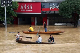Người dân đi thuyền qua khu vực ngập lụt do mưa lớn tại Khu tự trị dân tộc Choang Quảng Tây, Trung Quốc. (Ảnh: THX/TTXVN)