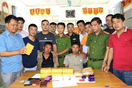 Hai đối tượng cùng tang vật tại cơ quan điều tra. (Ảnh: Xuân Tư/TTXVN)