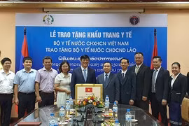 Ông Nguyễn Thanh Long trao khẩu trang (tượng trưng) tặng Đại sứ Lào tại Việt Nam Sengphet Houngboungnuang. (Nguồn: qdnd.vn)