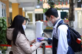 Học sinh thực hiện khử khuẩn trước khi vào lớp. (Ảnh: Nguyễn Nam/Vietnam+)