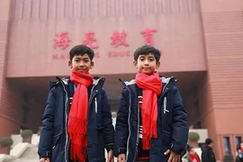 Thuch Salik (trái) đứng trước Trường Ngoại ngữ Hailiang ở tỉnh Chiết Giang, Trung Quốc. (Nguồn: Facebook/Thuch Salik)