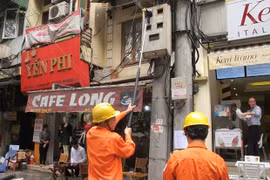 Nhân viên ngành điện đang chốt chỉ số công tơ của khách hàng. (Ảnh: Đức Duy/Vietnam+)