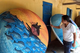 Những tác phẩm hội họa nhiều màu sắc, độc đáo được các họa sỹ thể hiện trên những chiếc thuyền thúng. (Ảnh: Đỗ Trưởng/TTXVN)