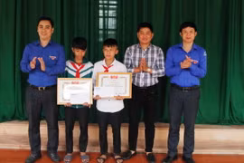 Trao bằng khen của Tỉnh đoàn và tiền thưởng cho hai em học học sinh Nguyễn Văn Chương và học sinh Nguyễn Phi Anh. (Ảnh: Phan Quân/TTXVN) 