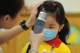 Kiểm tra thân nhiệt cho trẻ em tại một trường mầm non ở Hong Kong, Trung Quốc, để ngăn ngừa sự lây lan của dịch cúm. (Ảnh: AFP/TTXVN)