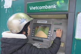 Một nữ công nhân đến rút tiền tại ATM Vietcombank. (Ảnh: Mạnh Minh/TTXVN) 