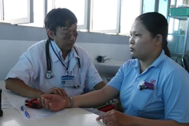 Bác sỹ kiểm tra sức khỏe cho công nhân Công ty trách nhiệm hữu hạn An Giang Samho. (Ảnh: Công Mạo/TTXVN) 