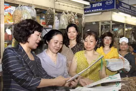 Vận động bà con tiểu thương chợ Đồng Xuân sử dụng túi giấy. (Ảnh: Thái Bình/TTXVN)