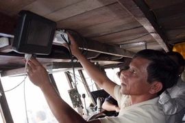 Lắp đặt thiết bị kết nối vệ tinh VMS cho tàu cá. (Ảnh: Trần Lê Lâm/TTXVN)