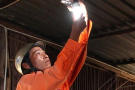 Lắp bóng đèn tiết kiệm điện cho hộ dân Kh'mer. (Ảnh: Ngọc Hà/TTXVN)