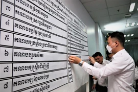 Nhân viên NEC niêm yết kết quả xếp thứ tự 18 chính đảng tham gia tổng tuyển cử năm 2023. (Ảnh: Huỳnh Thảo/ TTXVN)