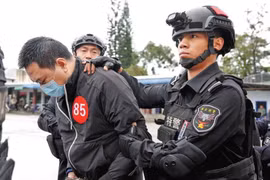 Một nghi phạm lừa đảo bị cảnh sát Trung Quốc áp giải. (Ảnh: China Daily) 