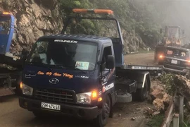 Đơn vị chức năng triển khai công tác cứu hộ cứu nạn xe ôtô bán tải bị đất đá rơi vào. (Ảnh: TTXVN phát)