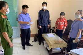 Cơ quan điều tra Viện Kiểm sát nhân dân Tối cao tống đạt Quyết định khởi tố bị can đối với bị can Nguyễn Thị Ngọc Tuyền (áo đỏ), nguyên thủ quỹ Chi cục Thi hành án dân sự huyện Thới Lai, thành phố Cần Thơ. (Ảnh: TTXVN phát)
