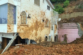 Hiện trường vụ sạt lở khiến căn nhà bị vùi lấp 1 phần. (Ảnh: Chu Quốc Hùng/TTXVN)