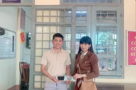 Anh Khánh trao trả tài sản nhặt được cho chị Vân. (Ảnh: TTXVN phát)