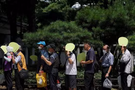 Người dân xếp hàng nhận cơm từ thiện dưới trời nắng nóng tại Seoul, Hàn Quốc ngày 1/8/2023. (Ảnh: Yonhap/TTXVN)
