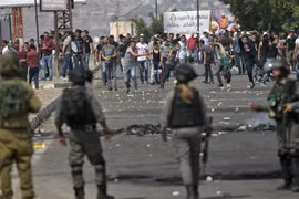 Người Palestine và các lực lượng Israel trong cuộc đụng độ tại Nablus ngày 15/5/2022. (Ảnh: AFP/TTXVN)