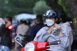Nhiệt độ giảm, nhiều người phải mặc thêm áo. (Ảnh: Hoàng Hiếu/TTXVN)