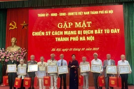 Phó Bí thư Thành ủy Hàn Nội Ngô Thị Thanh Hằng trao bằng khen cho các cá nhân là các chiến sỹ cách mạnh bị địch bắt tù đày. (Ảnh: Nguyễn Thị Tuyết Mai/TTXVN)
