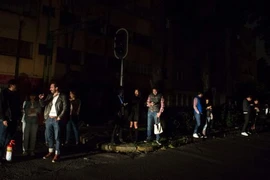 Người dân tại thành phố Mexico City kiểm tra điện thoại của họ trong bóng tối chạy ra khỏi nhà sau khi nghe còi báo động. (Nguồn: AP)