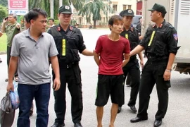 Lực lượng công an áp giải nghi can Đặng Văn Hùng. (Ảnh: Thế DuyệtTTXVN) 