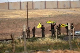 Binh sỹ người Kurd giương cờ sau khi chiếm được cửa khẩu Akcakale trên biên giới Syria - Thổ Nhĩ Kỳ ngày 15/6. (Nguồn: AFP/TTXVN) 