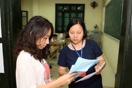 Cán bộ coi thi đối chiếu thông tin của thí sinh trong Kỳ thi Trung học phổ thông quốc gia 2018. (Ảnh: Thanh Tùng/TTXVN)