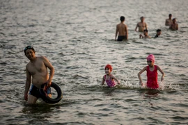 Trong những ngày nắng nóng đỉnh điểm ở Hà Nội, cứ vào tầm chiều muộn thời tiết mát mẻ, nhiều người dân đã kéo nhau ra khu vực hồ Tây để tắm giải nhiệt. (Ảnh: Minh Sơn/Vetnam+) 