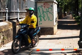 Nhiều người vẫn đi xe máy trên vỉa hè lắp thí điểm barie một thanh. (Ảnh : Hoàng Hải/TTXVN)