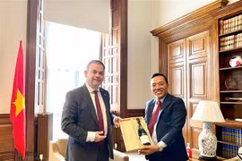 Quốc vụ khanh Nigel Adams trao quà tặng Đại sứ Nguyễn Hoàng Long. (Ảnh: TTXVN phát)
