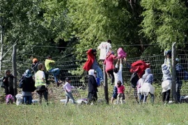 Người di cư vượt qua hàng rào tại khu vực làng Roszke, biên giới Hungary-Serbia. (Ảnh: AFP/TTXVN)