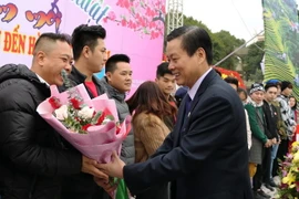 Chủ tịch UBND tỉnh Hà Giang Nguyễn Văn Sơn tặng hoa cho những du khách đầu tiên “xông đất” du lịch Hà Giang năm 2021. (Ảnh: TTXVN phát)