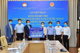 Phó Chủ tịch Ủy ban Trung ương Mặt trận Tổ quốc Việt Nam Trương Thị Ngọc Ánh trao kinh phí hỗ trợ phòng, chống dịch cho Thứ trưởng Bộ Ngoại giao, Chủ nhiệm Ủy ban Nhà nước về người Việt Nam ở nước ngoài Đặng Minh Khôi. (Ảnh: Minh Đức/TTXVN)