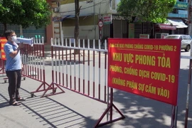 Lực lượng chức năng thông báo cho người trong khu phong tỏa tuân thủ biện pháp phòng dịch COVID-19. (Ảnh: Xuân Triệu/TTXVN)