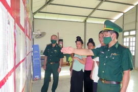 Cán bộ Đồn biên phòng cửa khẩu Chiềng Khương thuộc Bộ Chỉ huy Bộ đội Biên phòng tỉnh Sơn La, hướng dẫn người dân tìm hiểu về danh sách đại biểu Quốc hội và HĐND các cấp. (Ảnh: Hữu Quyết/TTXVN)