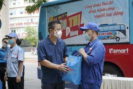 Chủ tịch Liên đoàn Lao động thành phố Hà Nội Nguyễn Phi Thường tặng “Túi An sinh Công đoàn” động viên người lao động Công ty Cổ phần Toyota Thăng Long. (Ảnh: TTXVN phát)