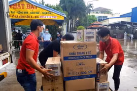 Đại diện Ban Quản lý các Khu chế xuất, Khu công nghiệp thành phố cùng Hiệp hội doanh nghiệp thành phố tặng quà cho công nhân đang cách ly trong Công ty thực phẩm Vạn Đức, Khu công nghiệp Vĩnh Lộc. (Ảnh: TTXVN phát)