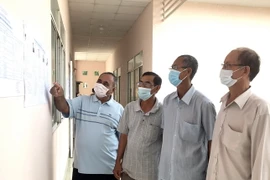 Cử tri đồng bào Khmer xã Trà Côn, huyện Trà Ôn xem danh sách người ứng cử đại biểu Quốc hội khóa XV. (Ảnh: Lê Thúy Hằng/TTXVN)