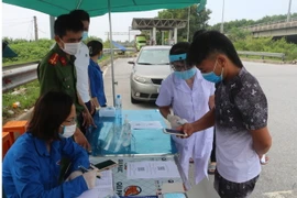 Khai báo y tế điện tử, quét mã QR tại chốt kiểm soát chân cầu nút giao Vực Vòng thuộc địa phận phường Yên Bắc, thị xã Duy Tiên, tỉnh Hà Nam. (Ảnh: Thanh Tuấn/TTXVN)