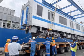 Các chuyên gia, kỹ sư, công nhân đưa toa xe xuống xe vận chuyển chuyên dụng. (Ảnh: TTXVN phát)