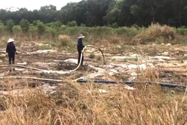 Công nhân Khu xử lý chất thải của Công ty TNHH Cù Lao Xanh đang xả nước thải ô nhiễm từ hồ chứa nước ra môi trường. (Ảnh: Văn Việt/Vietnam+)