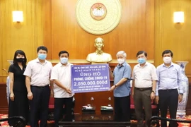 Chủ tịch Ủy ban Trung ương Mặt trận Tổ quốc Việt Nam Đỗ Văn Chiến tiếp nhận ủng hộ từ Bộ trưởng Bộ Kế hoạch và Đầu tư Nguyễn Chí Dũng. (Ảnh: Minh Đức/TTXVN)