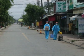 Nhân viên y tế lấy mẫu xét nghiệm người dân khu vực cách ly. (Ảnh: Thanh Bình/TTXVN)