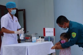 Tiến hành kiểm tra sức khỏe và hướng dẫn phụ huynh cách chăm sóc, phòng chống dịch COVID-19. (Ảnh: TTXVN phát)