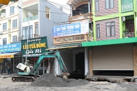 Lực lượng chức năng đang thực hiện việc san lấp hố tử thần rộng khoảng 100m2 xuất hiện nhiều ngày nay ở xã Quảng Bị, huyện Chương Mỹ, Hà Nội. (Ảnh: Lê Phú/TTXVN)